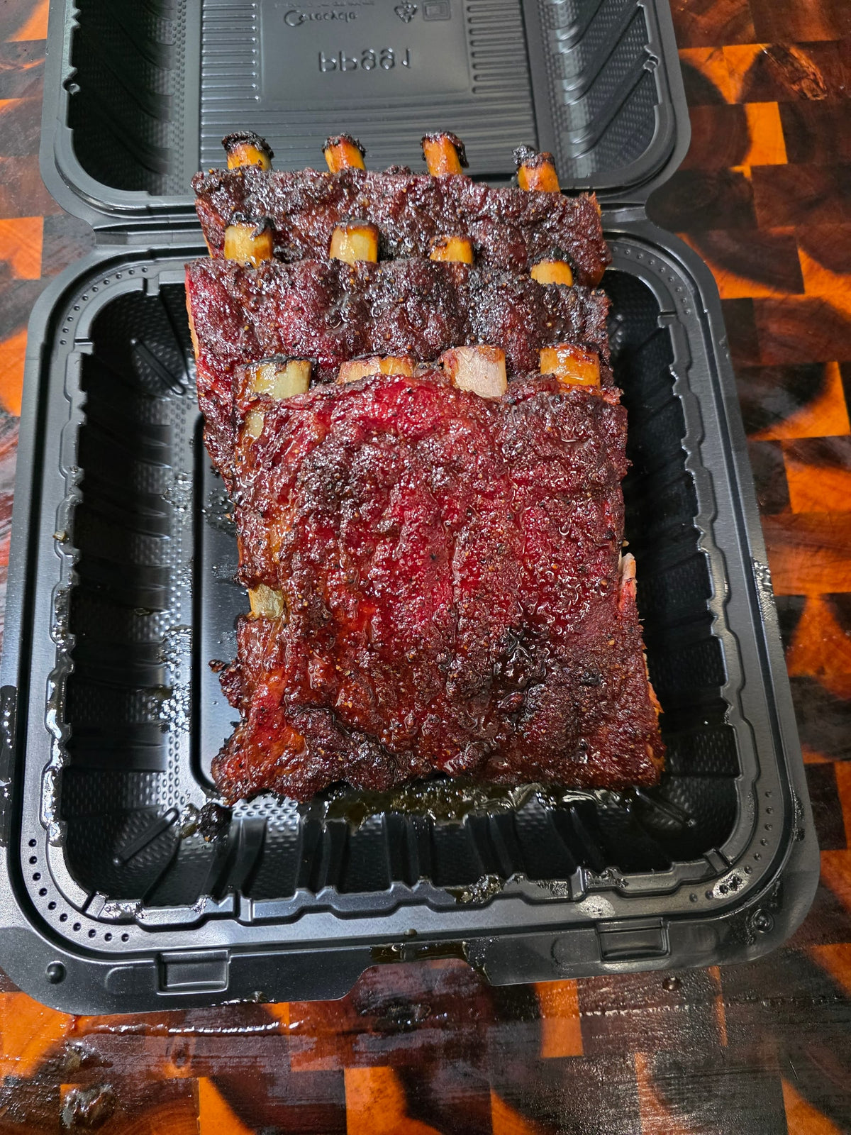 Rack of smoked ribs packed in a takeout container