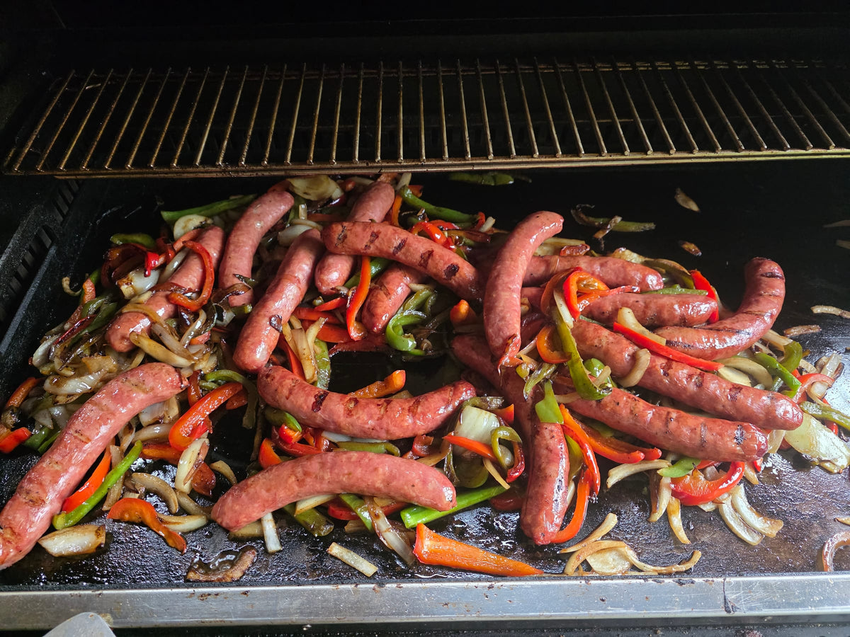 Smoked sausages with peppers and onions on the flat-top grill